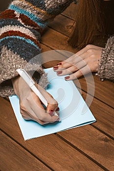 Woman Hands with Red Manicure on a Wooden Table Write a Greeting Card with a Pen. Woman Fill in a Letter on a Piece of