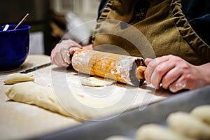 Woman hands rolling out dough in flour with rolling pin in her home kitchen. Selective focus