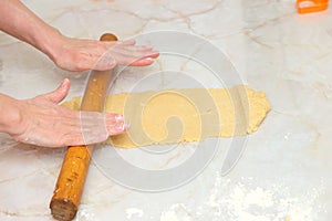 Woman hands rolling out dough with rolling pin, detail