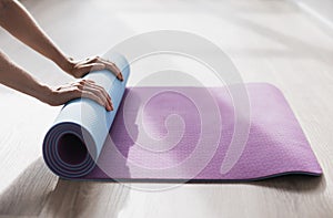 Woman hands rolling up exercise mat after doing yoga or fitness closeup.