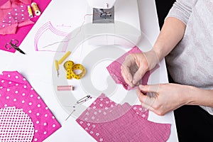 Woman hands sewing a pink ladies face mask during the coronavirus pandemia. photo