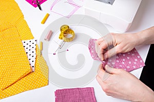 Woman hands sewing a pink ladies face mask during the coronavirus pandemia photo