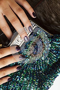 Woman hands with shiny manicure holding little purse peacok feather, cosmetic and fashion people concept