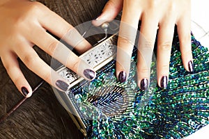 woman hands with shiny manicure holding little purse peacok feather, cosmetic and fashion people concept
