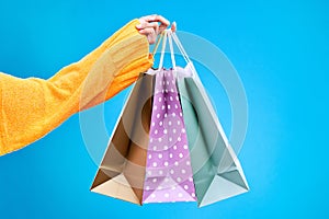 Woman, hands and shopping bags in studio of purchase, luxury accessories or sale against a blue background. Hand of