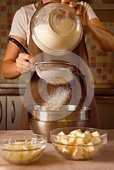 woman hands sifts flour through sieve for homemade cooking. saturate flour with air for tender texture of dough