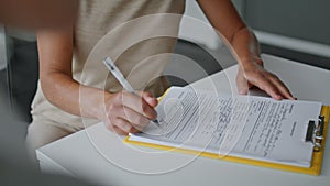 Woman hands signing papers sitting at table close up. Girl writing documents.