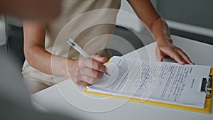 Woman hands signing papers sitting at table close up. Girl writing documents.