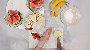 Woman hands slicing red apples, close up video, flat lay.