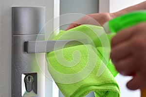 Woman hands spraying cleaning detergent on home door handle