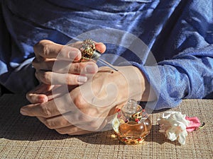 Woman hands spraying perfume on her wrist. Oriental woman gets the perfume oil on her wrists.