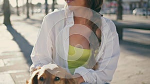 Woman hands stroking pet in summer street closeup. Happy girl rubbing ginger dog