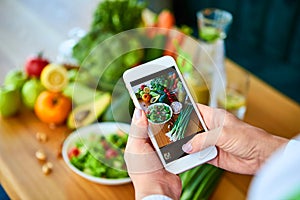 Woman hands take smartphone food photo of vegetables salad with tomatoes and fruits. Phone photography for social media or