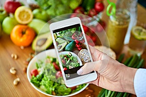 Woman hands take smartphone food photo of vegetables salad with tomatoes and fruits. Phone photography for social media or