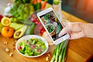 Woman hands take smartphone food photo of vegetables salad with tomatoes and fruits. Phone photography for social media or