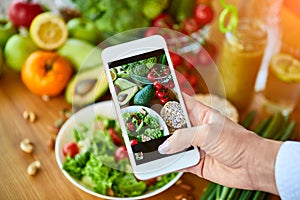 Woman hands take smartphone food photo of vegetables salad with tomatoes and fruits. Phone photography for social media or