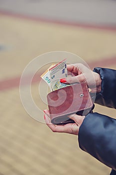 Woman hands taking money out of brown leather wallet