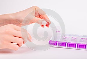 Woman hands taking pill or vitamin from organizer. Daily health treatment and medication concept.