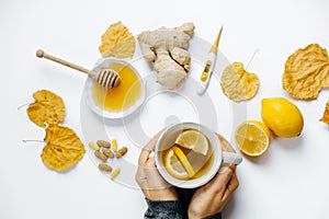 Woman hands with tea, lemon, thermometer, ginger, honey, tablets