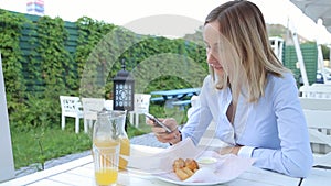 Woman hands texting on smartphone during breakfast in cafe