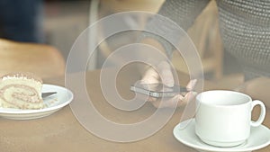 Woman hands texting on smartphone during breakfast in cafe
