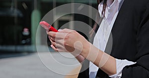 Woman hands texting on smartphone in the city street closeup. Unknown stylish businesswoman using telephone.