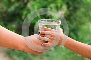 Woman hands to drink water with children hands green leaf background