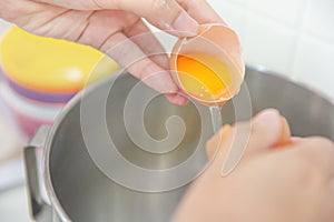 Woman hands to egg shells and separate egg yolk