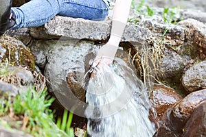 Woman hands in transparent water stream in supring park
