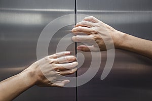 Woman hands try to stop doors of the closed elevator