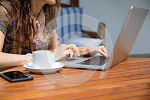 woman hands typing on keyboard pc laptop with coffee cup on table