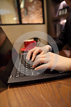 Woman hands typing in a laptop in a coffee shop