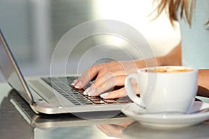 Woman hands typing in a laptop in a coffee shop