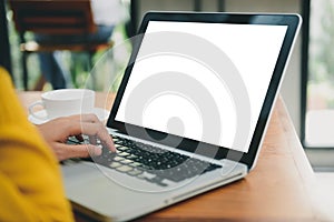 Woman hands typing laptop computer with blank screen on table in coffee shop. Blank laptop screen mock up for display of design.