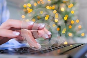 Woman hands typing on laptop computer keyboard with bokeh background - closeup