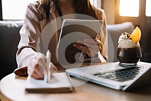 Woman hands is typing on a laptop and holding smartphone