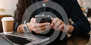 Woman hands is typing on a laptop and holding smartphone at office