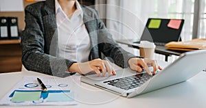 Woman hands is typing on a laptop and holding smartphone at office