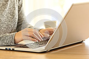 Woman hands typing in a laptop keyboard on a desk