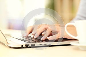 Woman hands typing on laptop keyboard at home