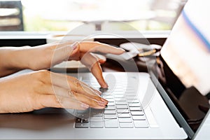 Woman hands typing on laptop keyboard. Woman working at office with coffee