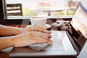 Woman hands typing on laptop keyboard. Woman working at office with coffee