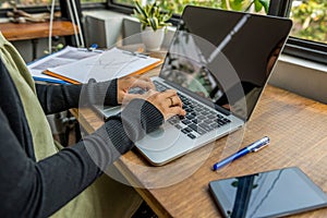 Woman hands typing laptop next to cellphone on wood table