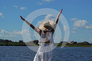 Woman hands up on riverside, back view