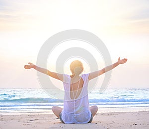 Woman with hands up at sunrise beach