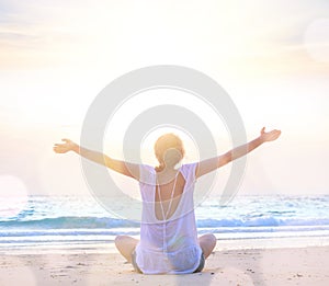 Woman with hands up at sunrise beach