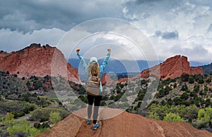 Woman with hands up on top of the mountain.