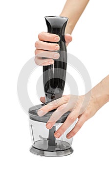 Woman hands using hand blender, which attached to chopping bowl.  on white