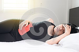 Woman hand using hot water bag or bottle on her belly and sleep on bedroom,Stomachache,Abdominal surface