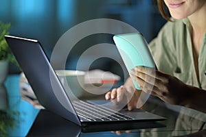 Woman hands using phone and laptop in the night